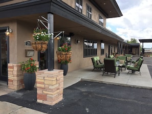 A building with outdoor seating, hanging flower baskets, and a brick planter. - Rodeway Inn & Suites Williams Downtowner - Rte 66 (Williams)