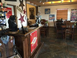 Una zona de bar con mostrador, sillas de madera y diversas decoraciones en la pared, incluyendo estrellas y letreros.
