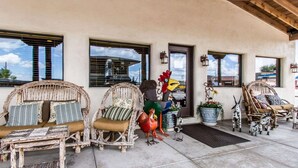 A covered patio with wicker furniture, decorative bird sculptures, and potted plants. - Rodeway Inn & Suites Williams Downtowner - Rte 66 (Williams)
