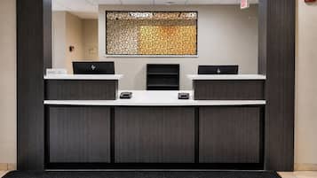 A reception desk with two HP computers, a decorative wall, and a fire alarm.