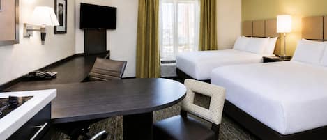Quarto de hotel com escrivaninha, duas camas, uma cadeira, televisão e janela com cortinas.