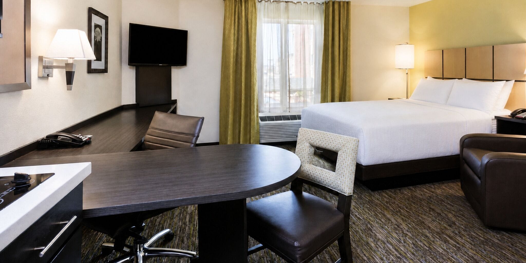A hotel room with a bed, a desk, a chair, a television, and a telephone.