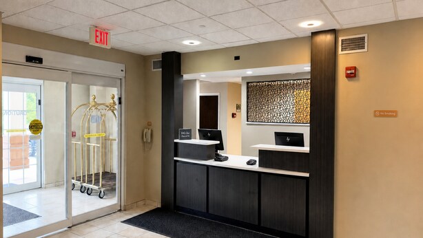 A reception area with a glass door entrance, a reception desk, a telephone, and a 'No Smoking' sign. - Candlewood Suites Pearl by IHG (Pearl)