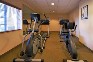 Sala de ginástica com esteiras e equipamentos elípticos.