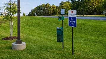 A grassy area with a sign indicating a pet walking area and a sign for Canleywood Suites.