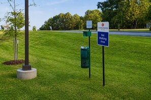 A grassy area with a sign indicating a pet walking area and a sign for Canleywood Suites. - Candlewood Suites Pearl by IHG (Pearl)