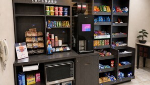 A coffee shop kiosk with a variety of coffee beans, snacks, and a coffee machine. - Candlewood Suites Pearl by IHG (Pearl)