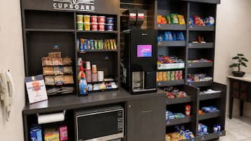 A coffee shop kiosk with a variety of coffee beans, snacks, and a coffee machine.