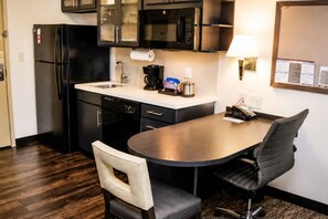 A compact kitchen with a refrigerator, microwave, coffee maker, and a small dining table with chairs. - Candlewood Suites Pearl by IHG (Pearl)