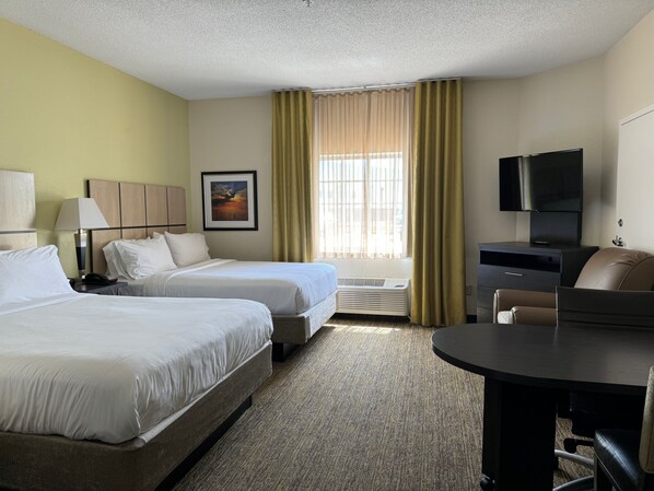 A hotel room with two beds, a desk, a chair, a TV, and a window with curtains. - Candlewood Suites Olive Branch by IHG (Olive Branch)
