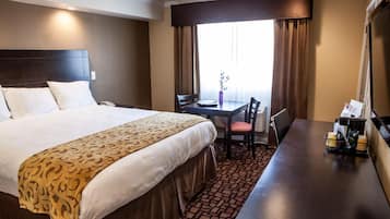 Una habitación de hotel con una cama grande, un escritorio y una silla.
