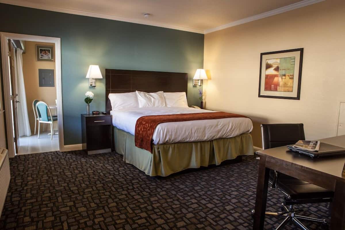 A hotel room with a bed, bedside tables, a desk, and a chair.