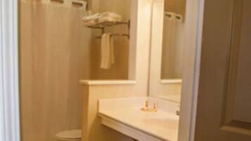 A bathroom with a toilet, shower, and sink.