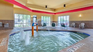 An indoor pool with multiple water jets, chairs around the perimeter, and large windows allowing natural light. - Comfort Suites Oshkosh West (Oshkosh)