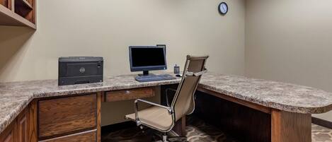 Un bureau avec un ordinateur, une chaise et une horloge au mur.