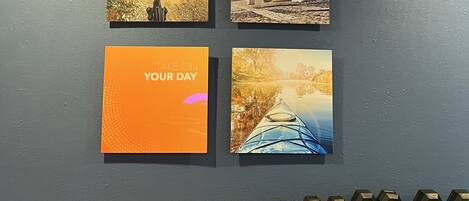 A wall with four framed pictures, a motivational poster, and a row of dumbbells.