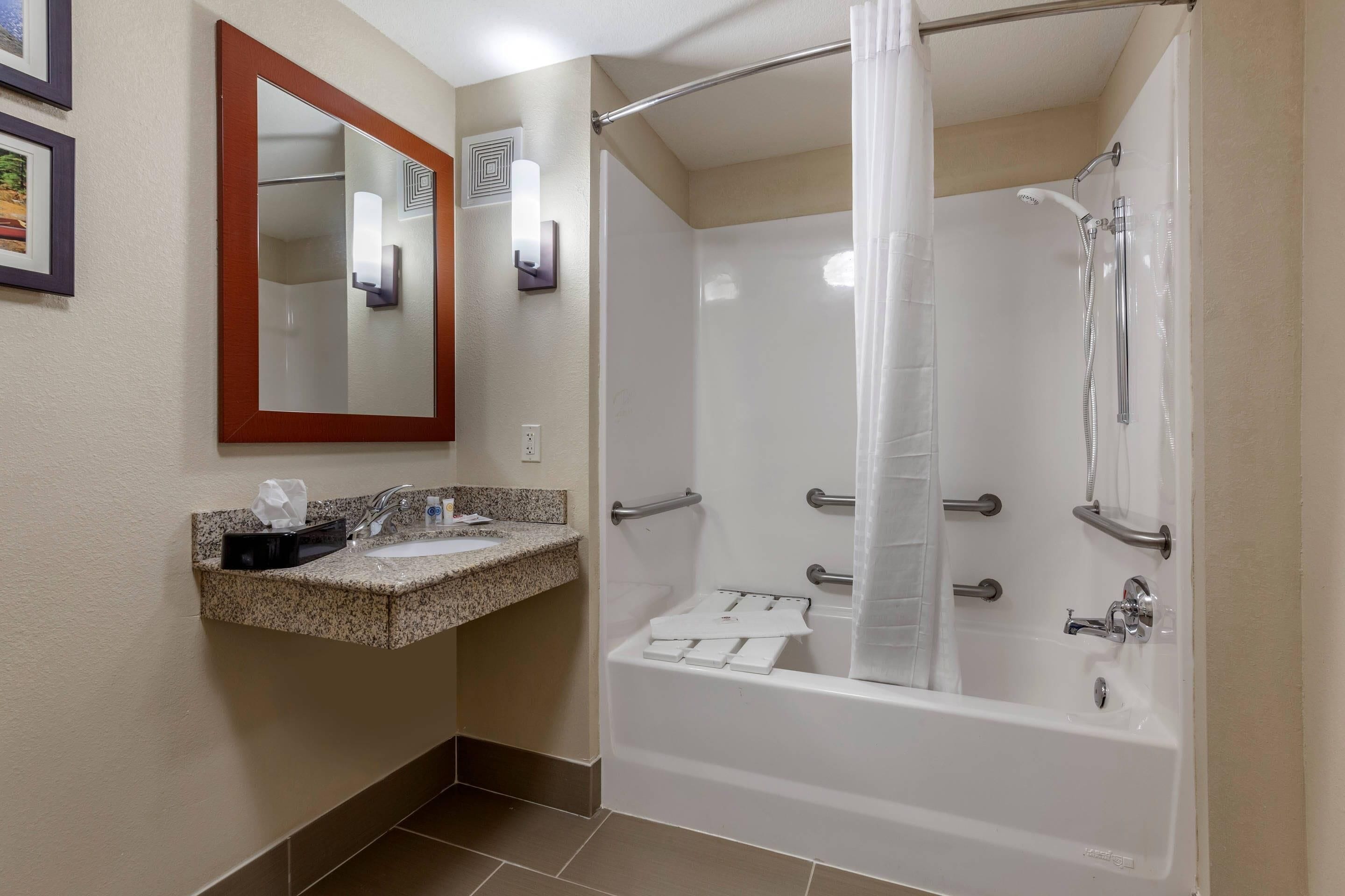A bathroom with a sink, mirror, shower, and towel rack.