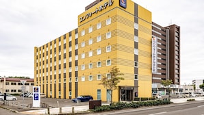 A multi-story hotel with a yellow facade, multiple windows, and a sign indicating it is a Carlson hotel. - Comfort Hotel Tomakomai (Tomakomai)