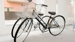 Un vélo avec un panier, garé à l’intérieur, avec une fenêtre en arrière-plan.
