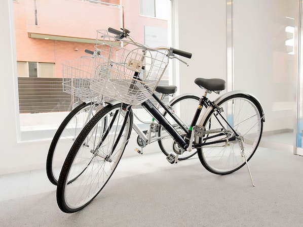 Un vélo avec un panier, garé à l’intérieur, avec une fenêtre en arrière-plan.