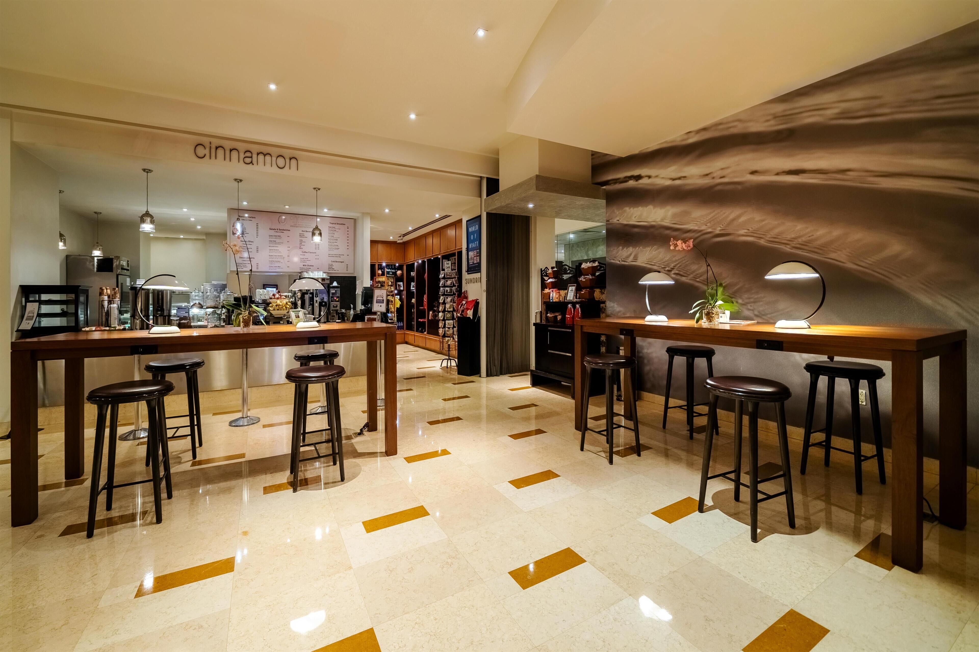 Uma área de bar moderna com banquetas, um quadro de cardápio e uma seção com tema de canela.