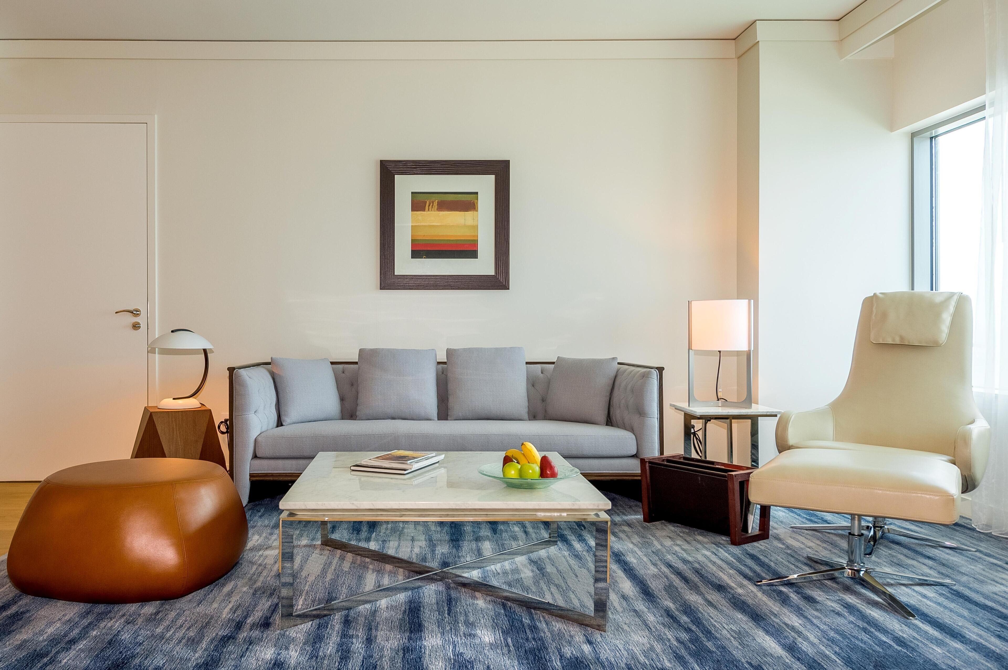 Een moderne woonkamer met een bank, een bijzettafeltje met fruit, een stoel en een lijst met een foto aan de muur.