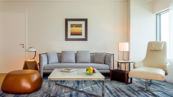 Een moderne woonkamer met een bank, een bijzettafeltje met fruit, een stoel en een lijst met een foto aan de muur.