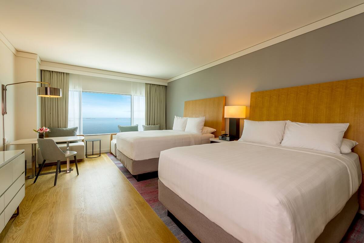 A hotel room with two beds, a desk, and a chair.