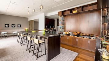 Una cocina moderna con una isla central, taburetes de bar, armarios de madera y una zona de buffet.