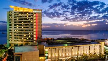 A high-rise hotel with a prominent 'Hyatt Regency' sign, a waterfront view, and a modern architectural design.