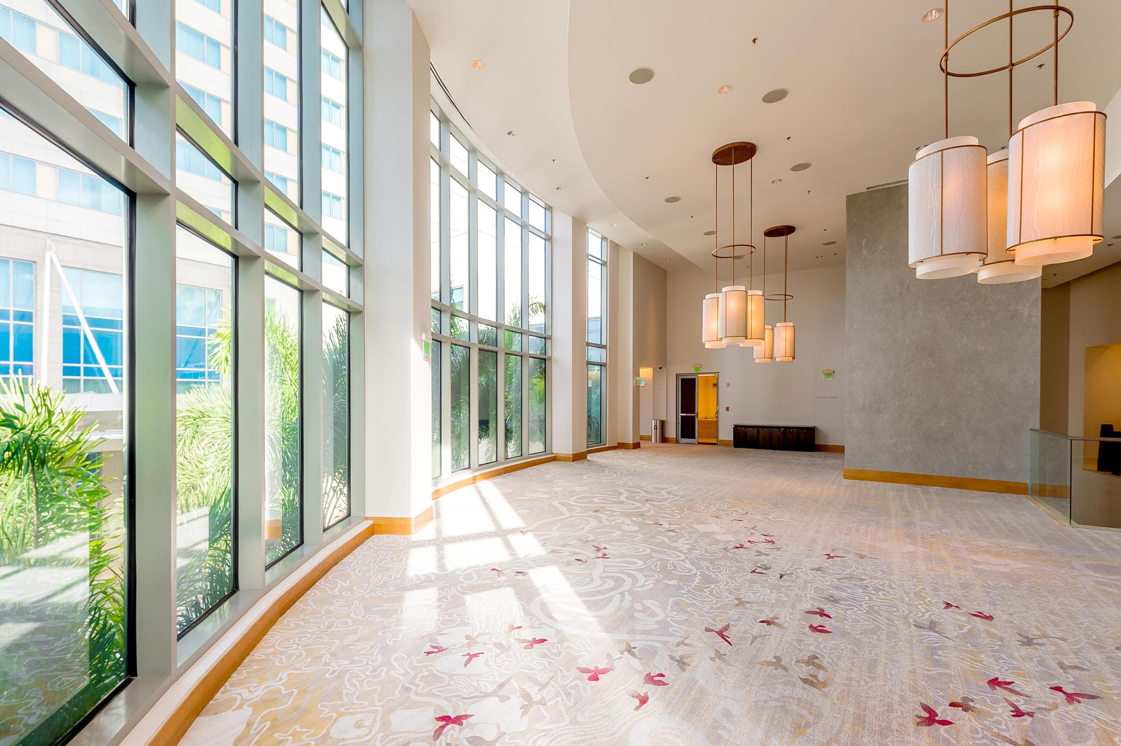 A spacious lobby with large windows, a patterned floor, and hanging pendant lights.