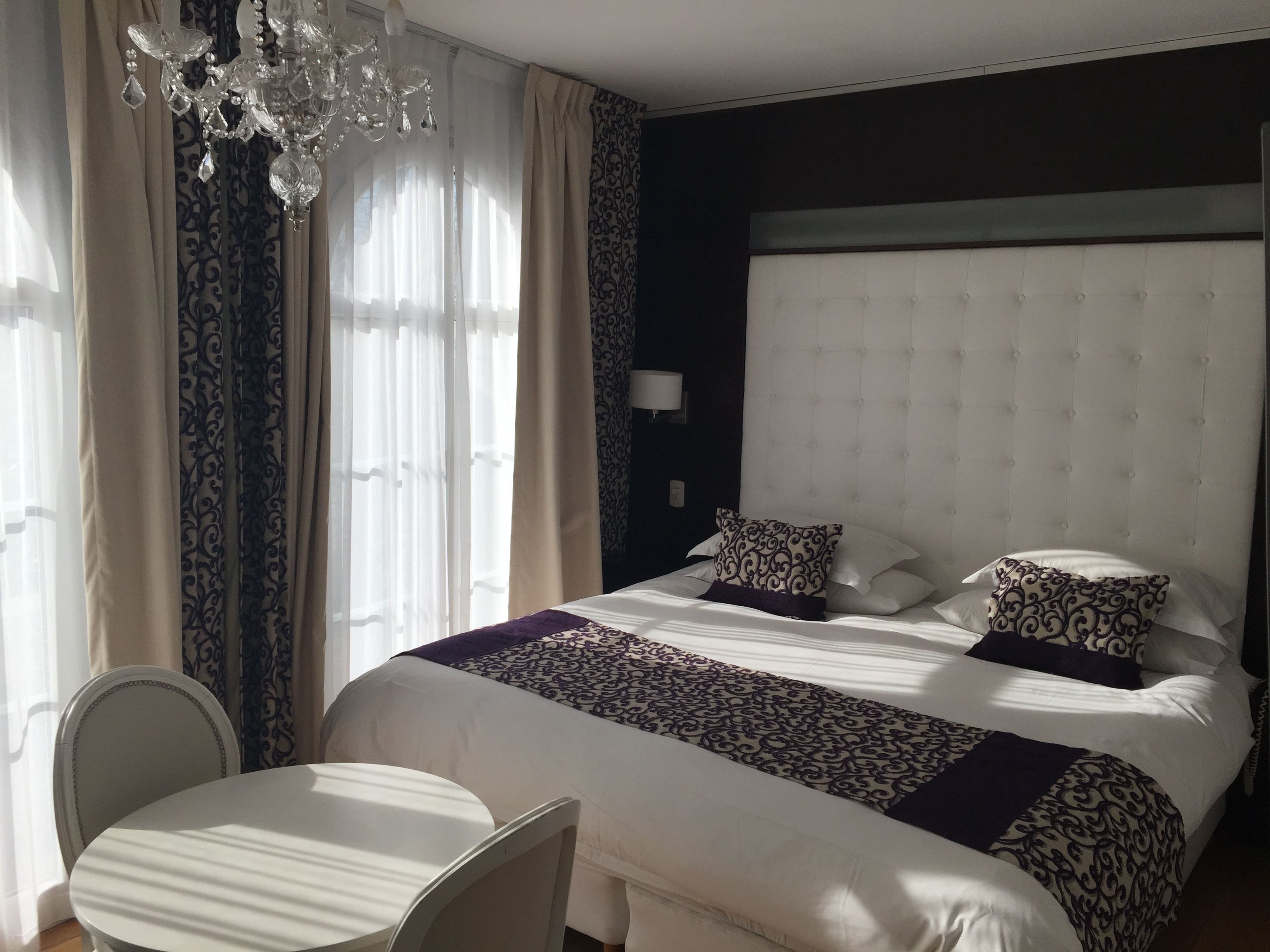Een hotelkamer met een groot bed, een kroonluchter, een tafel en een stoel.