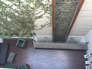 Een modern buitengebied met een tegelvloer, een glazen balustrade en potplanten.