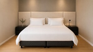 Een moderne slaapkamer met een groot bed, twee nachtkastjes en een nachtkastje met een lamp.
