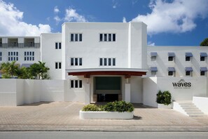 Moderni rakennus, jossa on tasakatto, useita ikkunoita ja kyltti, jossa lukee: ”Waves Resort & Spa – Barbados”.