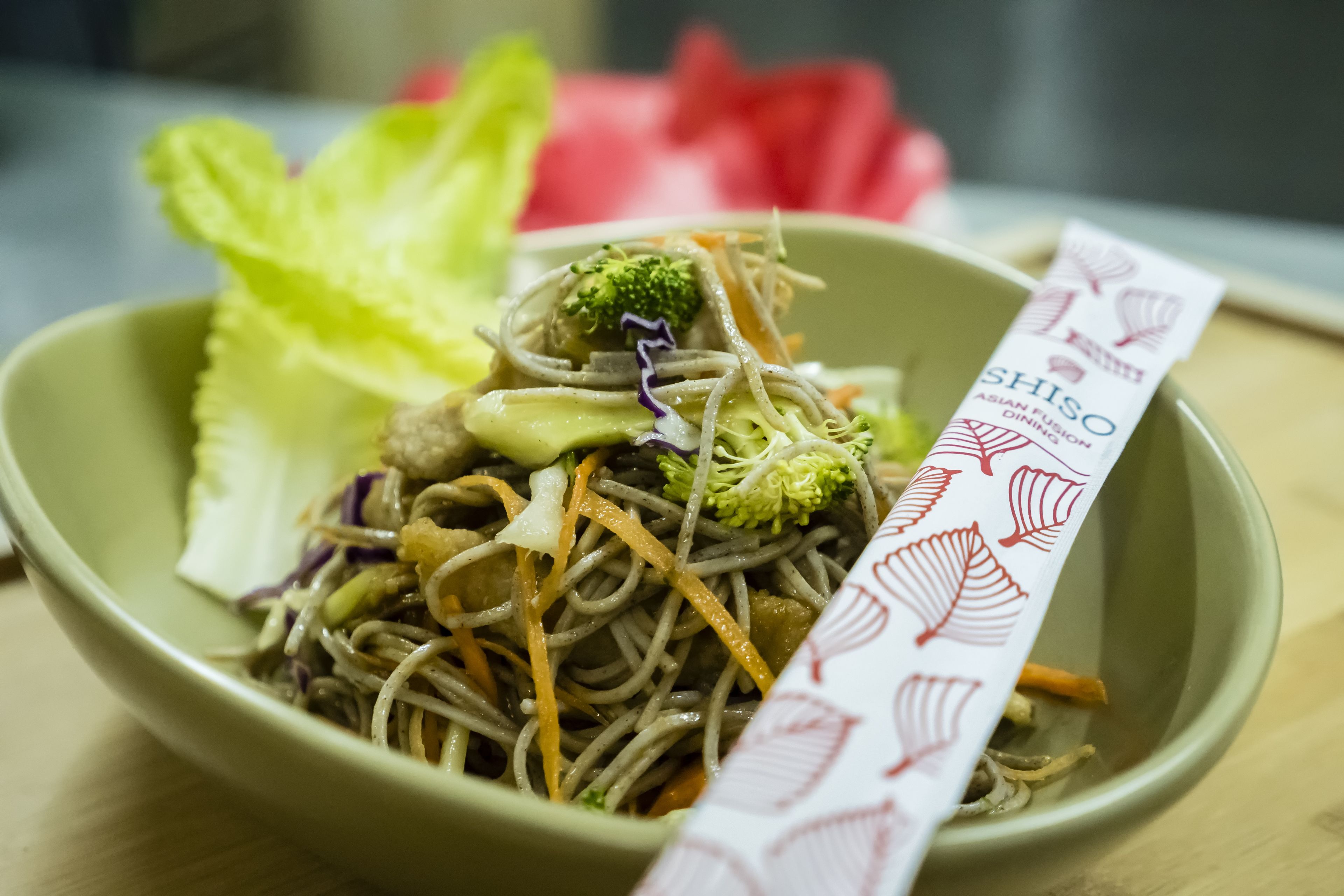Un tazón de fideos de fusión asiática con vegetales y una etiqueta.