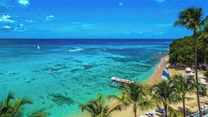 A beach with clear turquoise waters, a boat named "Off The Rock," and palm trees along the shore. - Waves Resort & Spa, Barbados, An Autograph Collection® All-Inclusive Resort (Prospect)