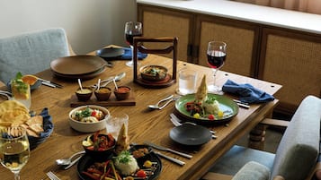 Una mesa de comedor de madera dispuesta con varios platos, copas de vino y cubiertos.