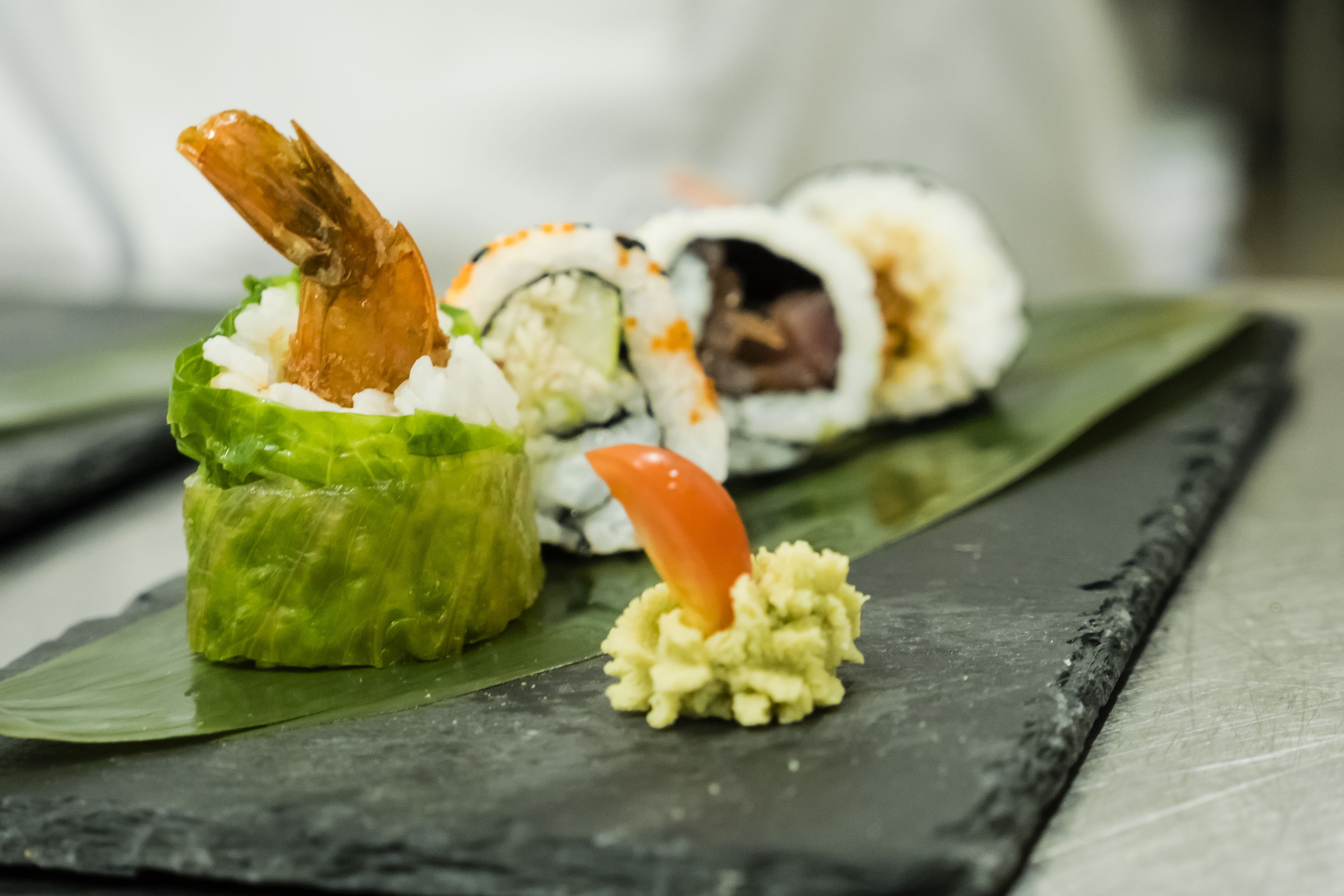 A sushi dish with a shrimp on top, placed on a dark slate plate.