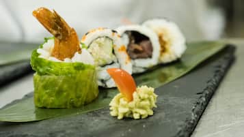 A sushi dish with a shrimp on top, placed on a dark slate plate.