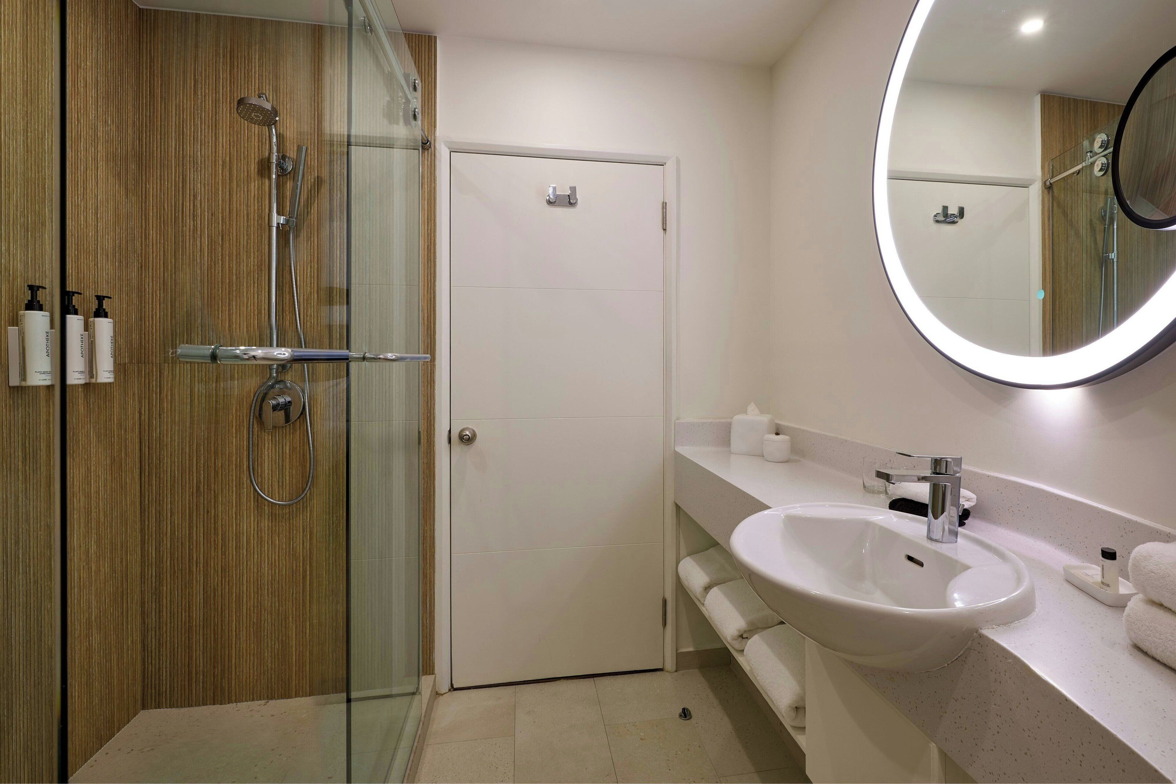 A modern bathroom with a glass-enclosed shower, a white sink, and a large mirror.