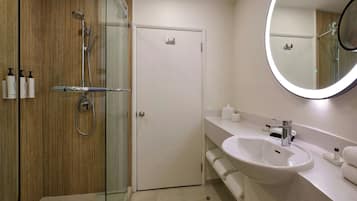 A modern bathroom with a glass-enclosed shower, a white sink, and a large mirror.