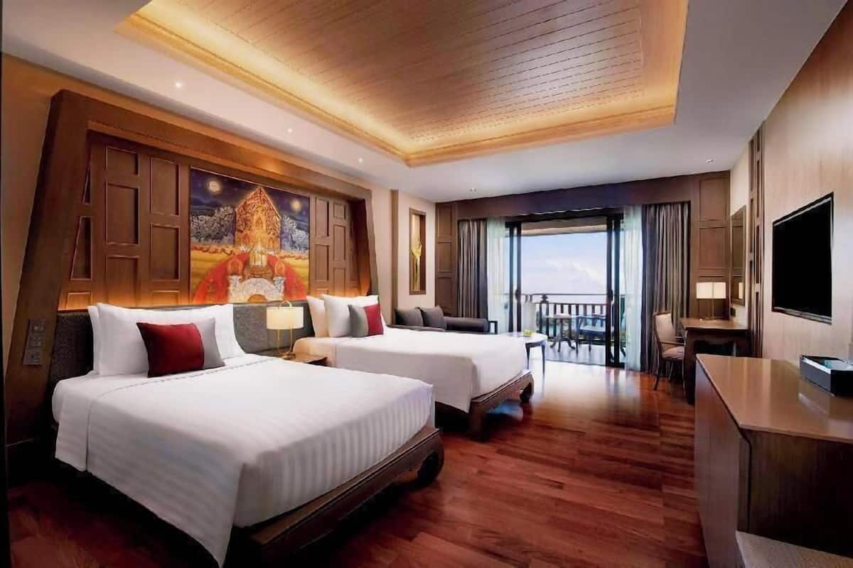 Een hotelkamer met twee bedden, een televisie, een bureau en een balkon met uitzicht.
