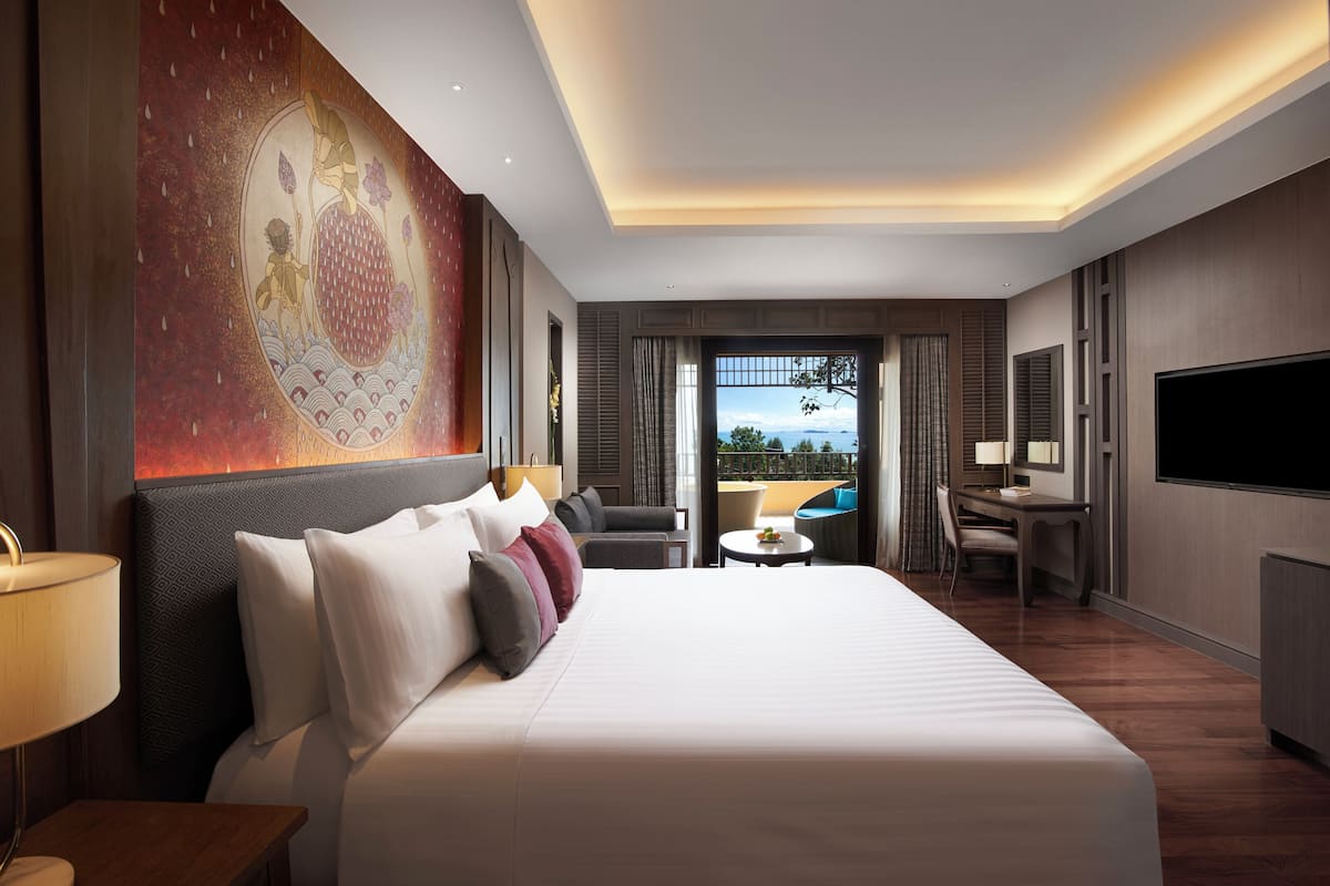 Een hotelkamer met een groot bed, een bureau, een stoel, een televisie en een balkon met uitzicht.