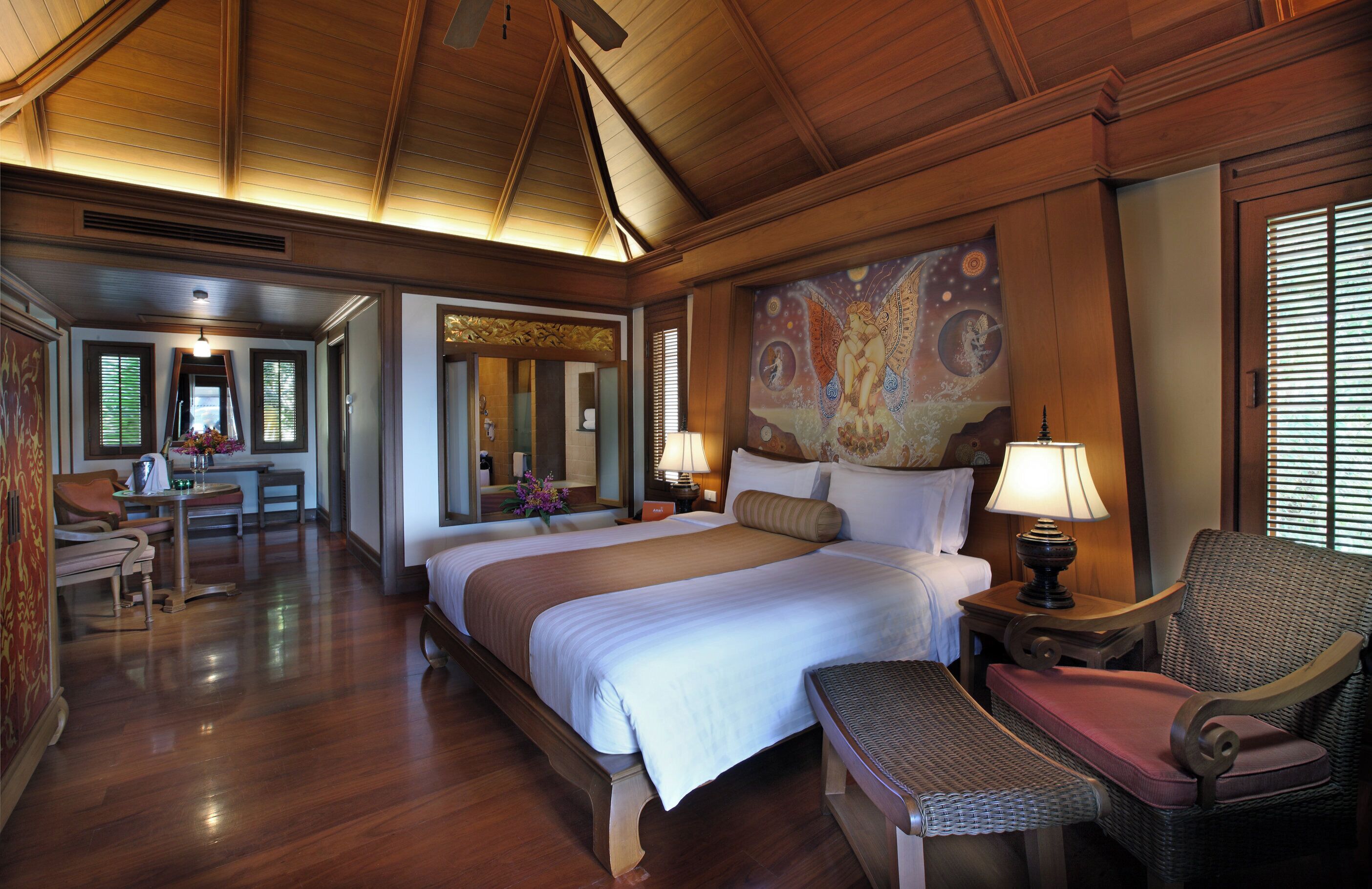 A spacious hotel room with a large bed, a sitting area with a chair and table, and a dining area with a table and chairs.