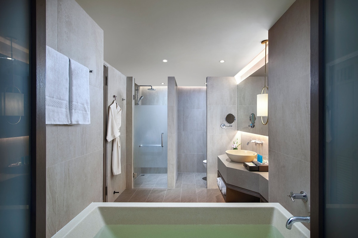 Une salle de bain moderne dotée d’une grande baignoire, d’une douche à l’italienne et d’un meuble-lavabo avec un évier et un miroir.