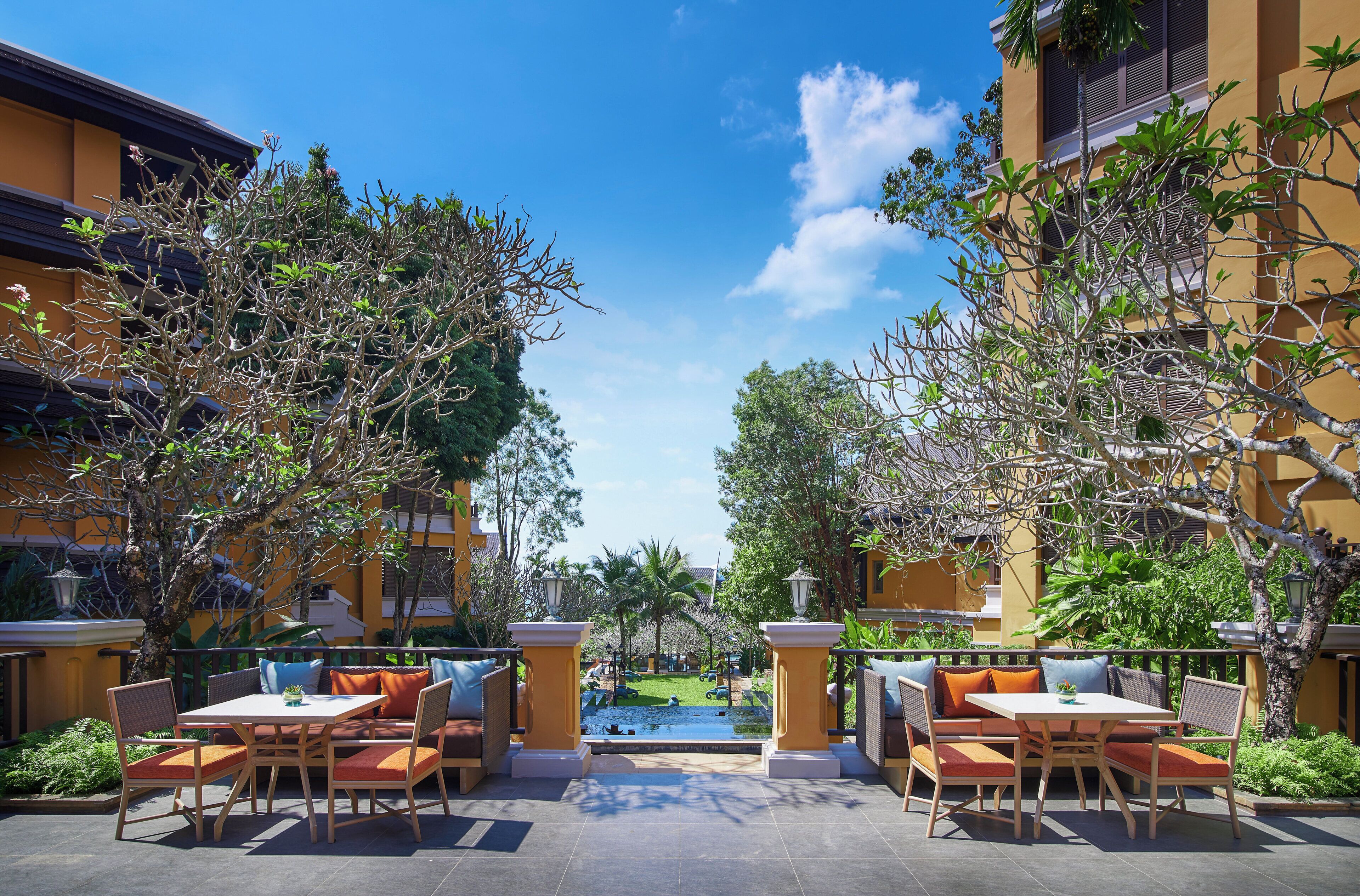 An outdoor seating area with tables and chairs, a small pool, and surrounding greenery.