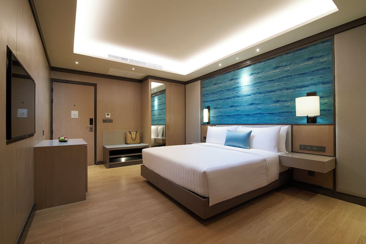 Een moderne hotelkamer met een groot bed, een bureau, een stoel en een tv aan de muur.