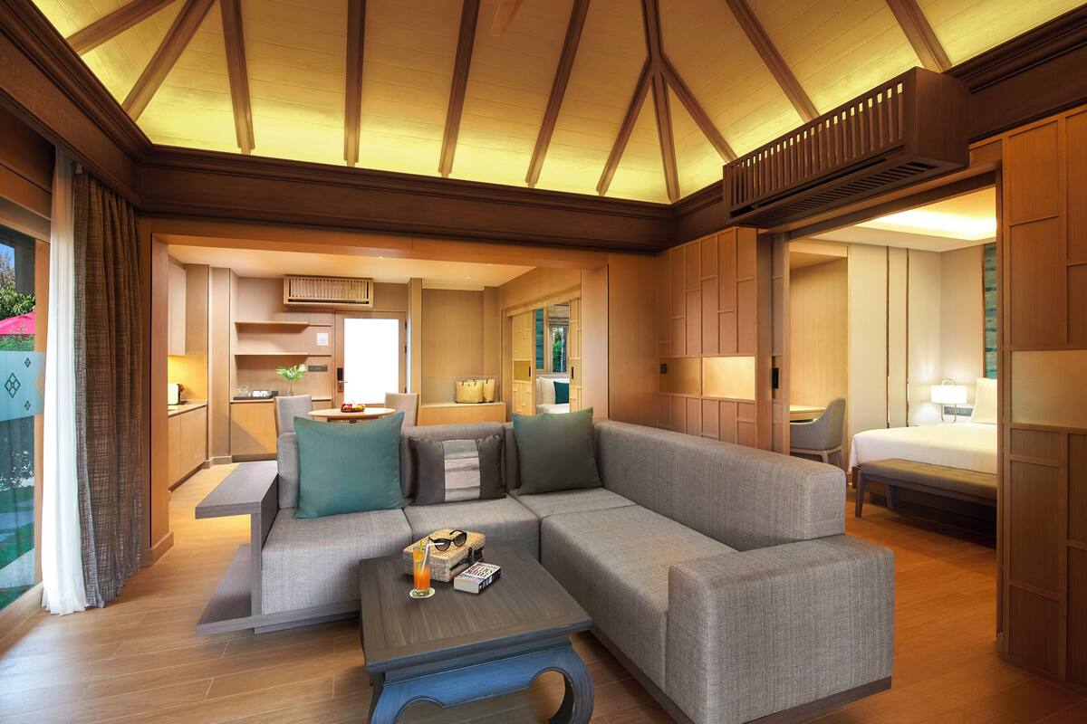 Een moderne hotelkamer met een hoekbank, een klein bijzettafeltje, een bureau en een bed.