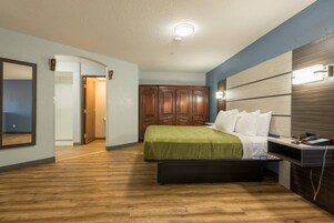 Habitación de hotel con cama, armario de madera y escritorio con silla.